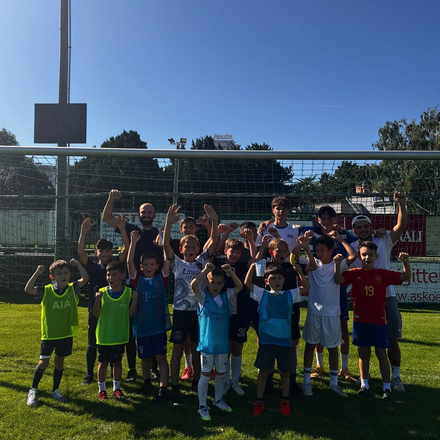 Gruppe von Kindern und Trainern beim Fußballtraining auf dem Platz in Wien jubelt nach Mini-Turnier